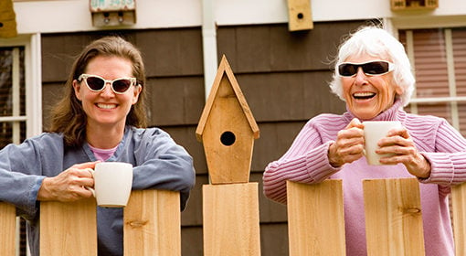 Photo of two women leaning on a fence