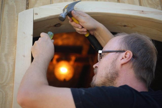 Alauna Yust’s husband hammers the door frame of their tiny home.