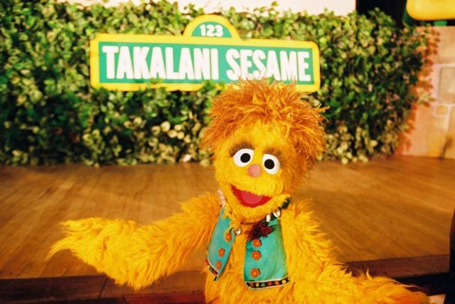 Kami, the first HIV-positive Muppet, poses in front of a sign from “Sesame Street’s” South African co-production, “Talakani Sesame.”