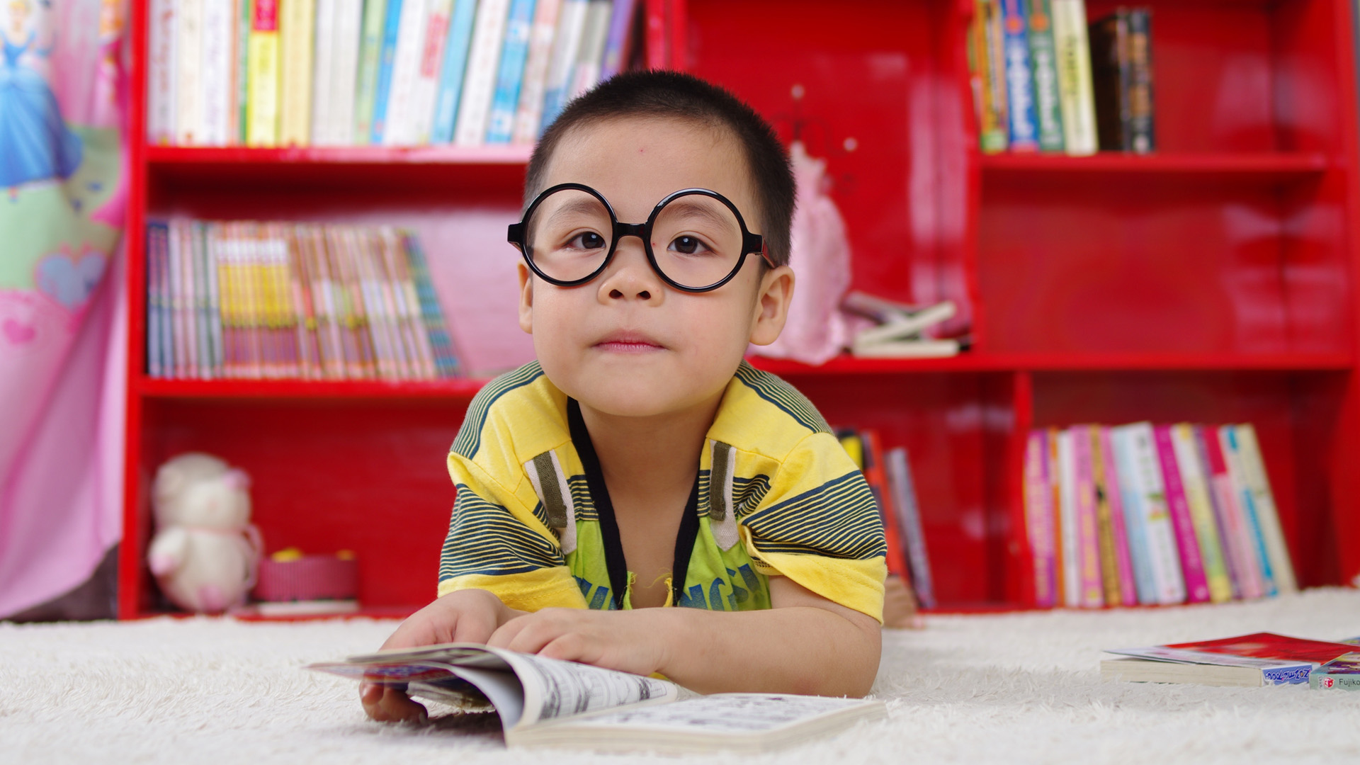 Child in glasses reading a book