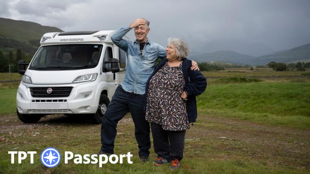 Miriam and Alan stand in a Scottish field laughing.