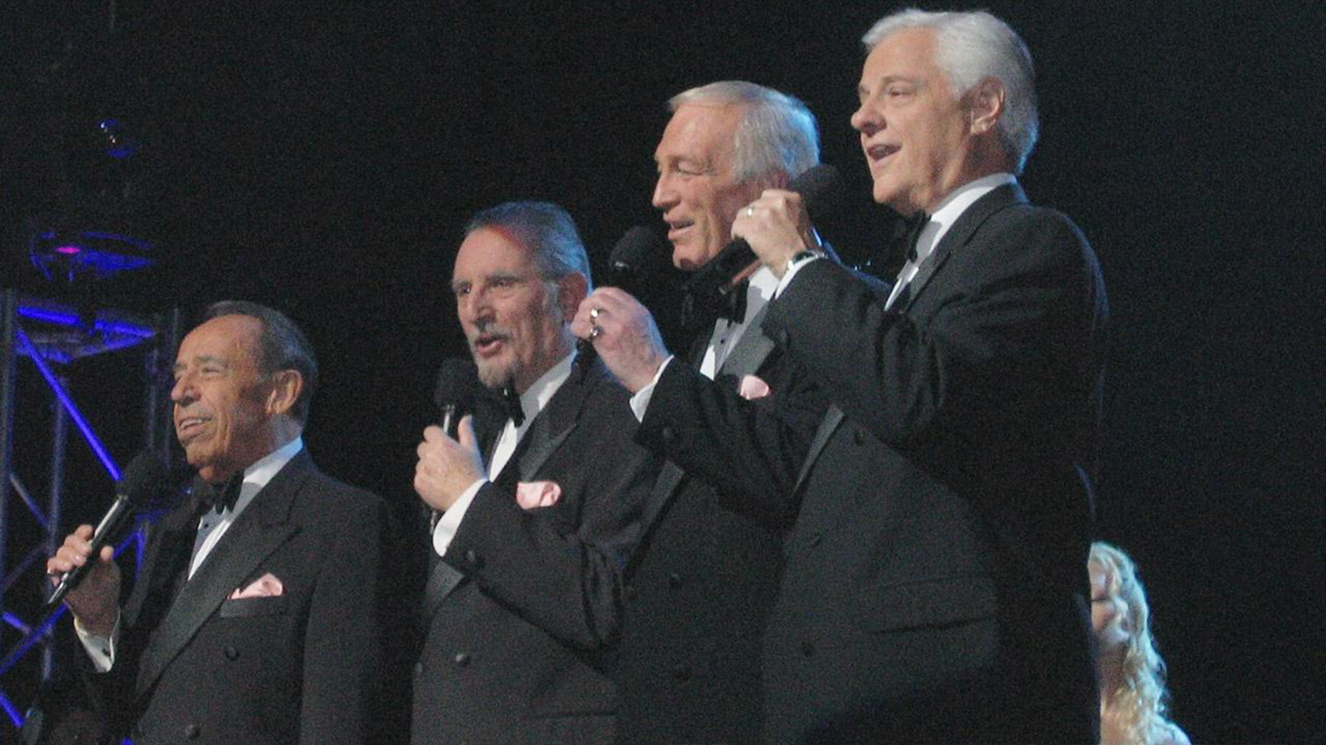 Four men on stage sing.